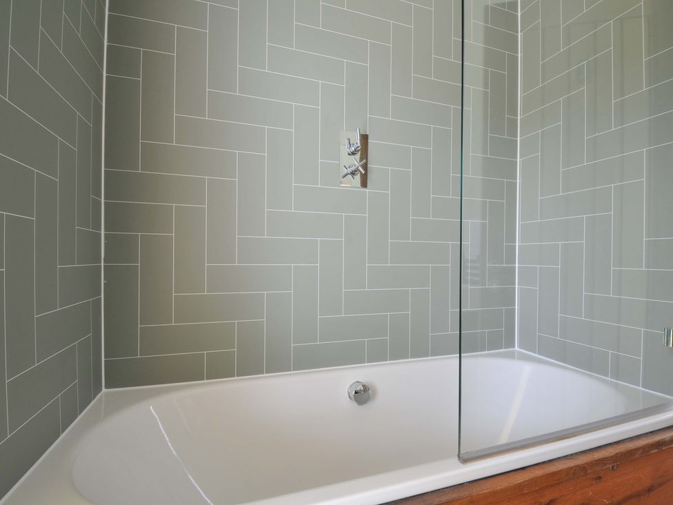 A bathroom with a bathtub and tiled wall at 4 Southern Place in Dobwalls