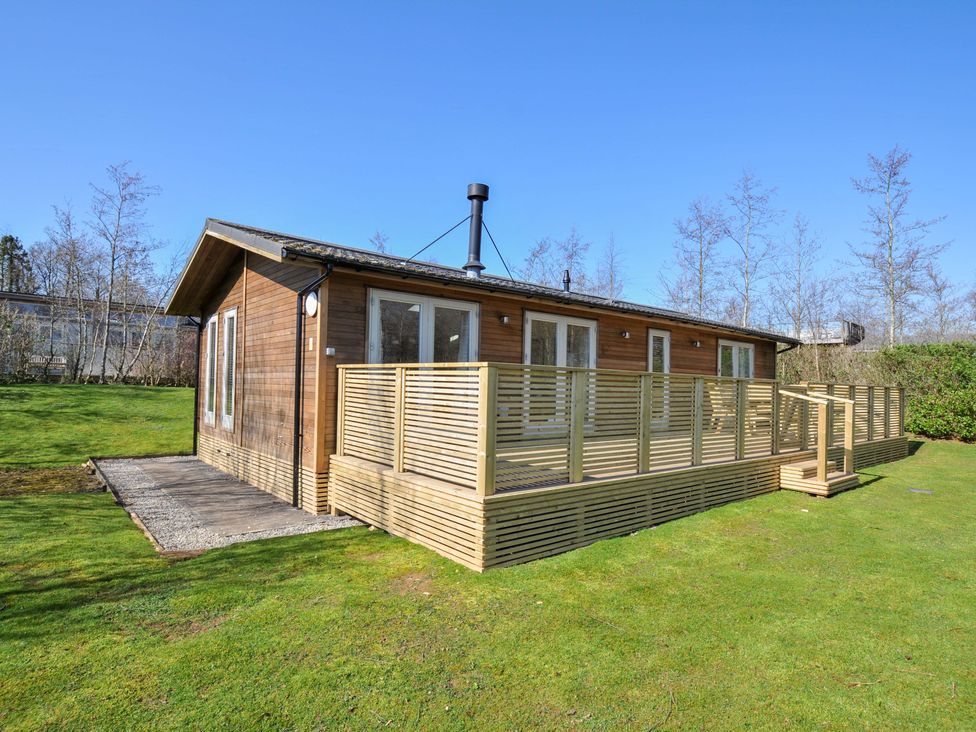 A wooden cabin with a deck and lawn at 4 Southern Place in Dobwalls