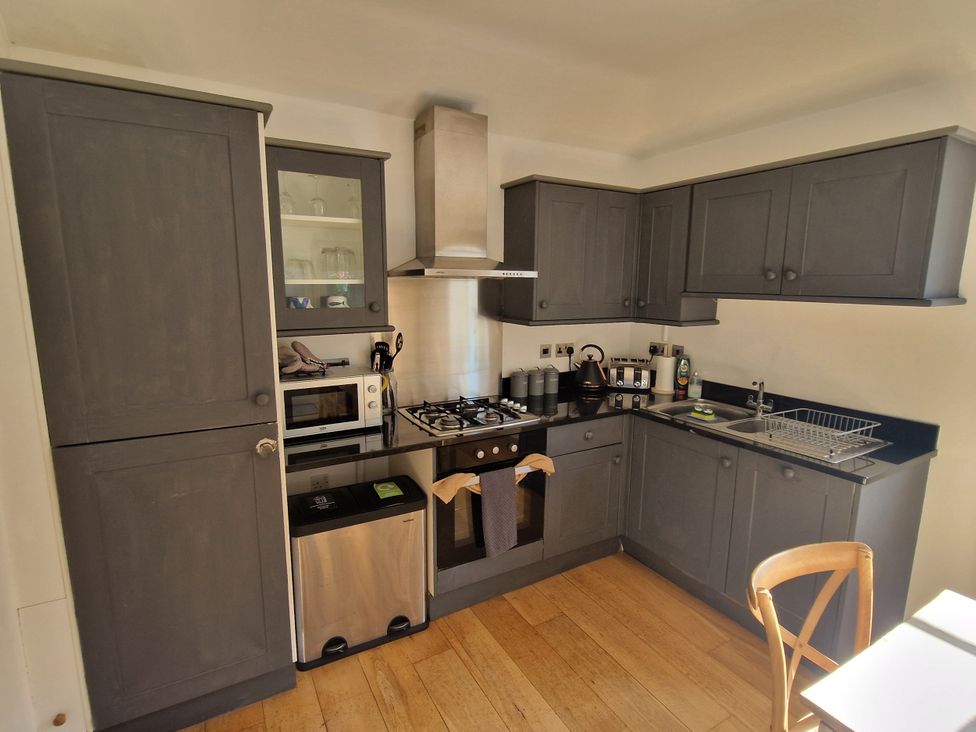 A kitchen with cabinets, stove, microwave, and sink at Flat 3 in Ross-on-Wye