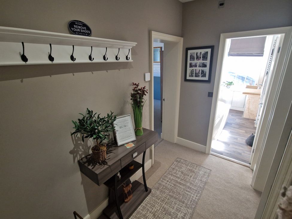 A hallway with coat hooks and a console table at Flat 3 in Ross-on-Wye