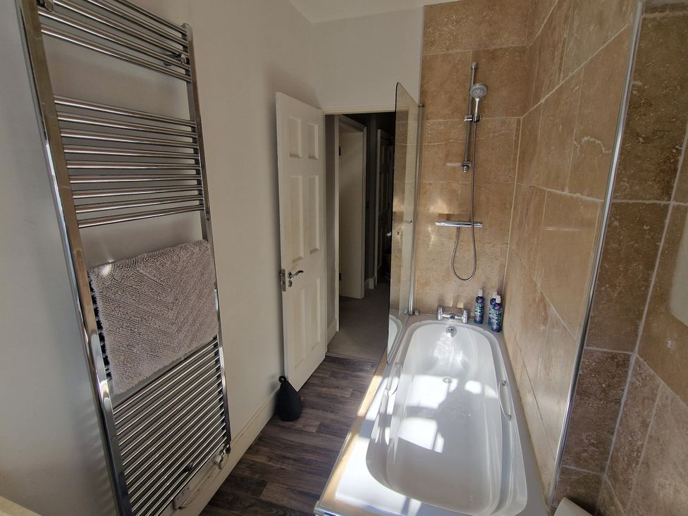 A bathroom with a bathtub and towel rail at Flat 3 Ross-on-Wye