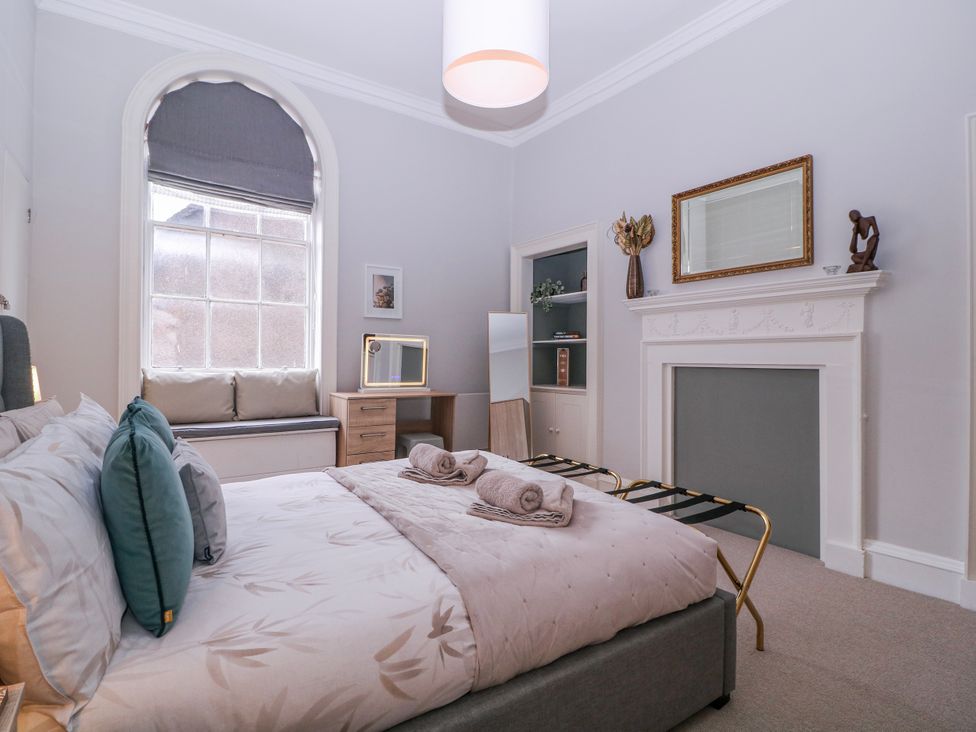 A bedroom with a bed, side table, and window at Stylish Town Apartment in Ross-On-Wye