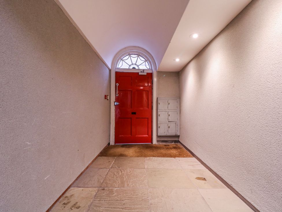 A hallway with a red door and mailboxes at Stylish Town Apartment in Ross-On-Wye