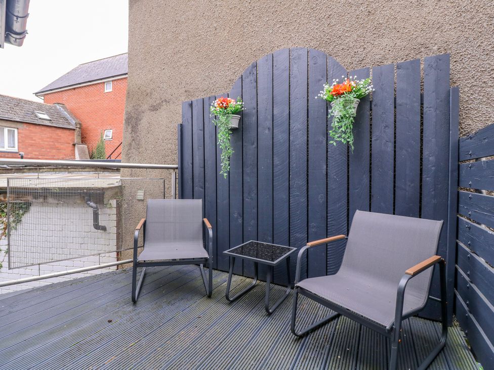 An outdoor area with two chairs, a table, and flower pots at Stylish Town Apartment in Ross-On-Wye