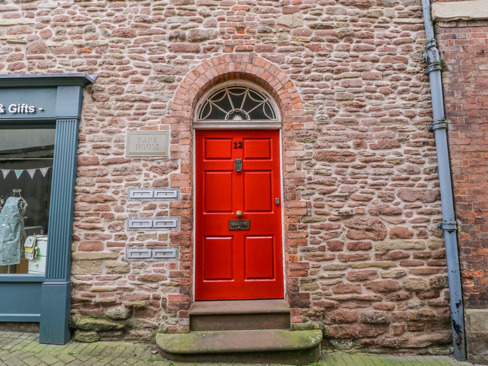 A red door with a nameplate and mailboxes at Bank House in Ross-On-Wye