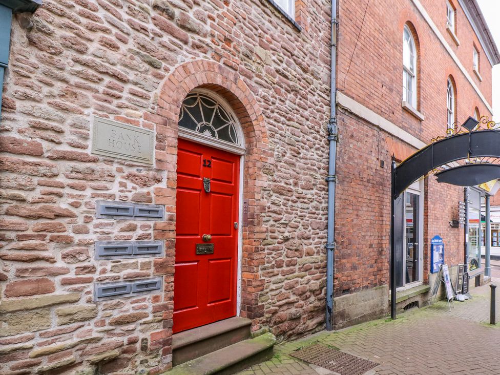 An entrance with a red door and stone wall at Bank House in Ross-On-Wye