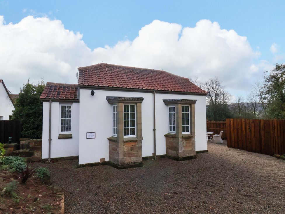 A cottage with a gravel area and wooden fence at Little Acorn in Whitby