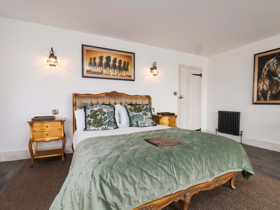 A bedroom with a bed, bedside table, and paintings at Hawthorn Lodge in Whitby