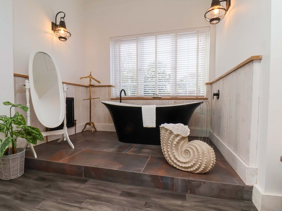 A bathroom with a bathtub and mirror at Hawthorn Lodge in Whitby