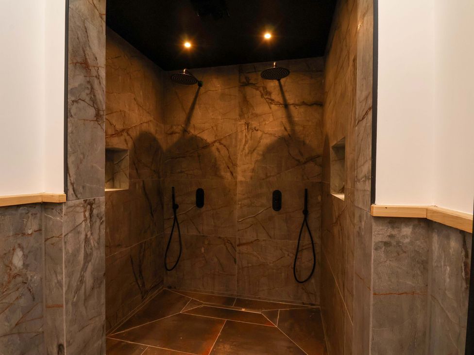 A shower area with stone walls and two shower heads at Hawthorn Lodge in Whitby