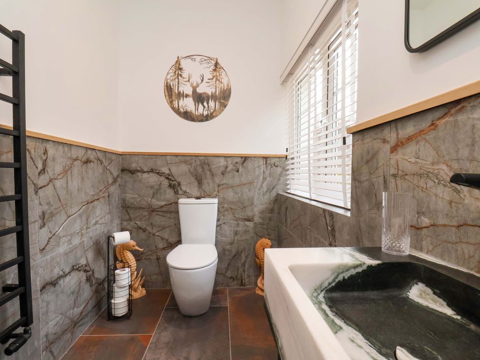 A bathroom with a toilet, sink, and window at Hawthorn Lodge in Whitby