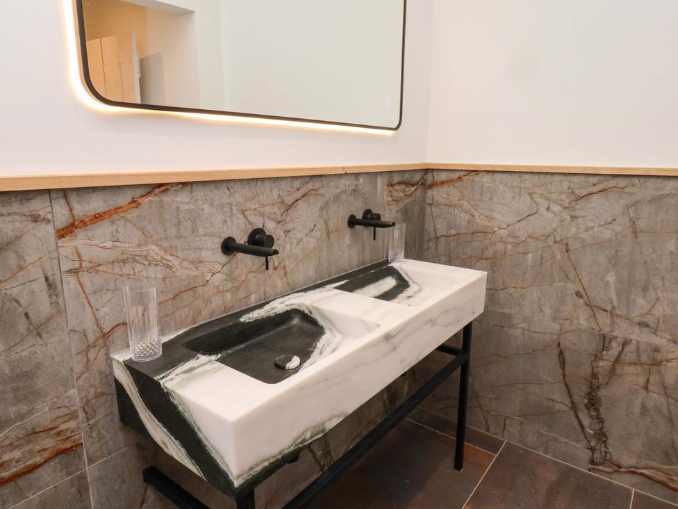 A bathroom with a marble sink and wall-mounted faucets at Hawthorn Lodge in Whitby