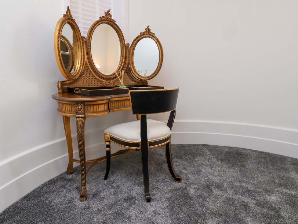 A vanity table with mirrors and a chair at Hawthorn Lodge in Whitby