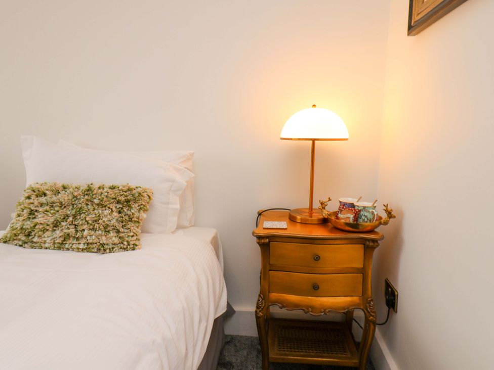 A bedroom with a bed and a lamp on a nightstand at Hawthorn Lodge in Whitby
