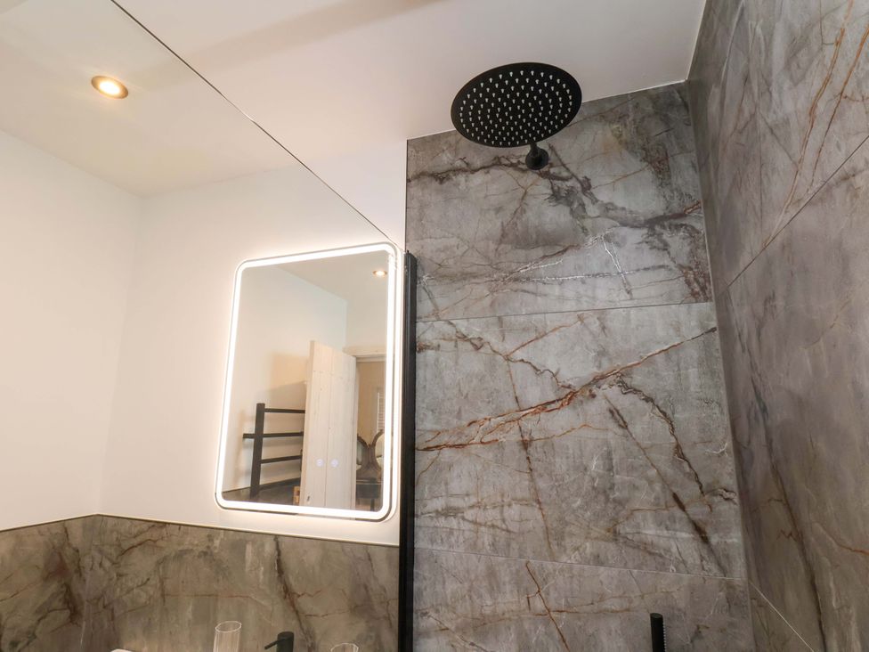 A bathroom with a shower head and mirror at Hawthorn Lodge in Whitby