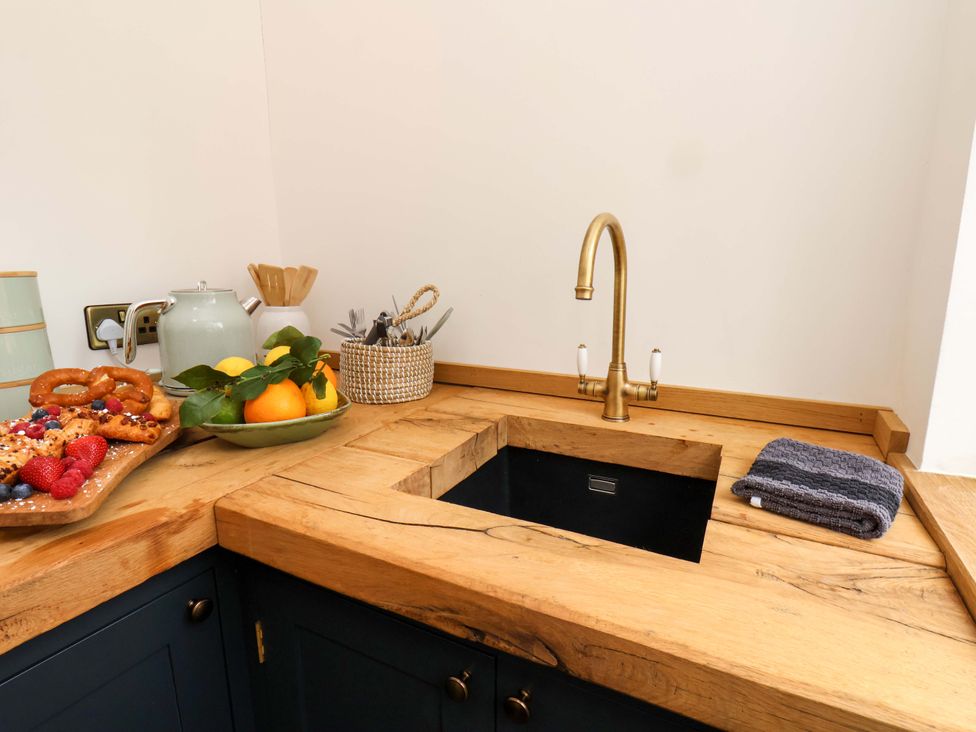A kitchen with a sink and countertop displaying fruits and pastries at Hawthorn Lodge in Whitby