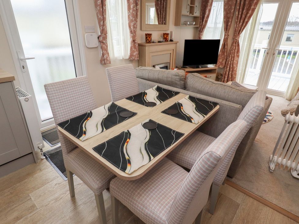 A dining table with chairs and a television in Cresswell Towers