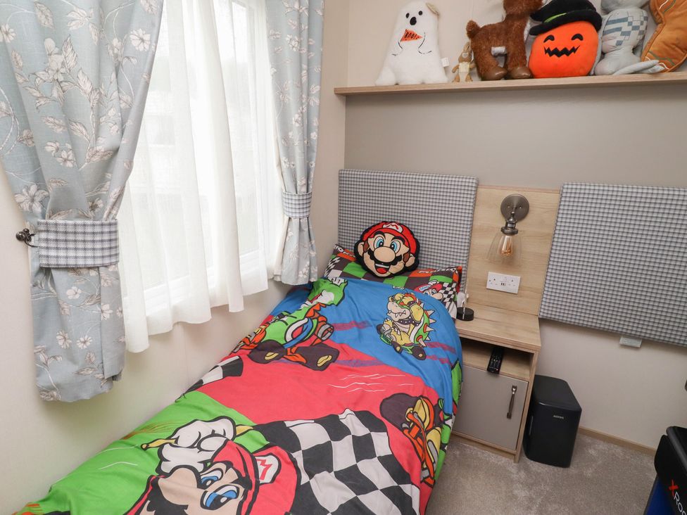 A bedroom with a bed featuring a colorful Mario-themed bed sheet at Cresswell Towers 