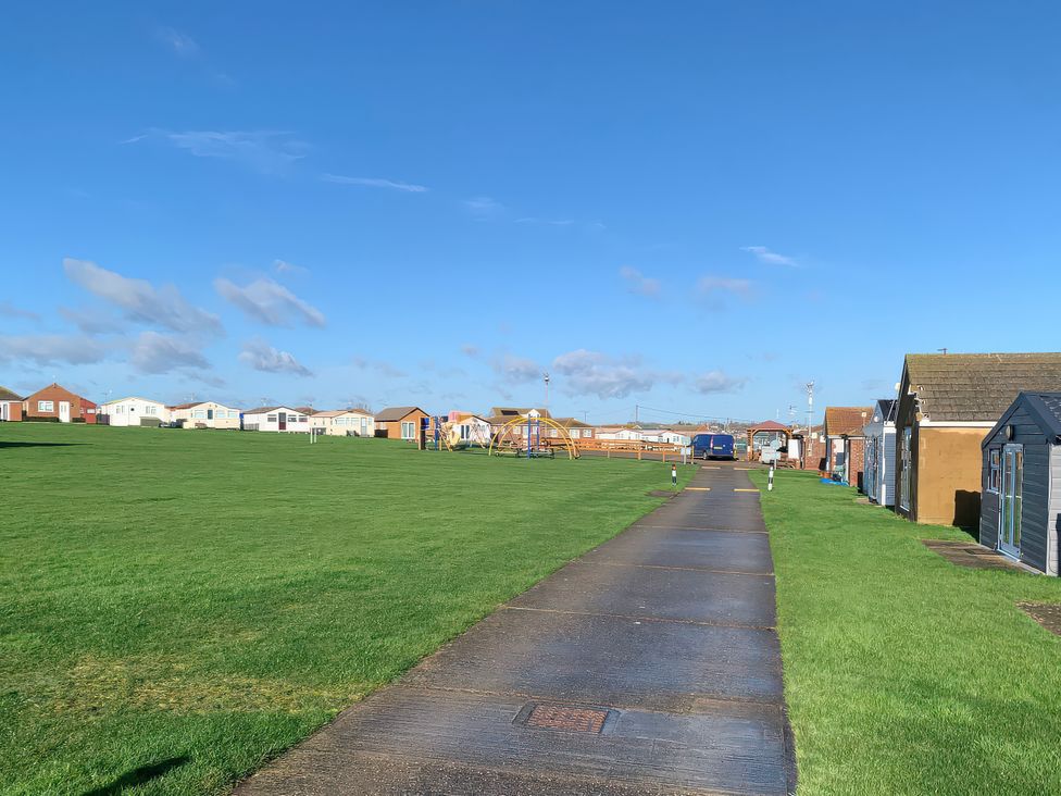 An outdoor area with a pathway and holiday cabins at Salt Air 130 @ Park Ave Holiday Village, Leysdown-On-Sea, Kent