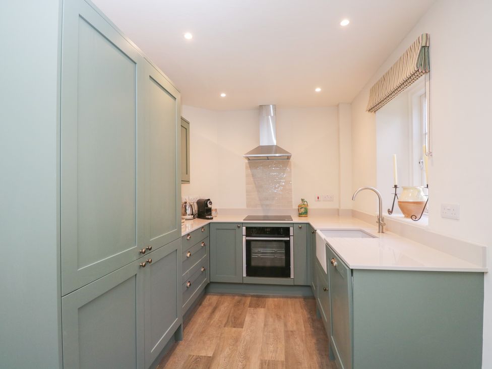 A kitchen with cabinets, oven, sink, and window at Middle Cottage Tisbury, Wiltshire