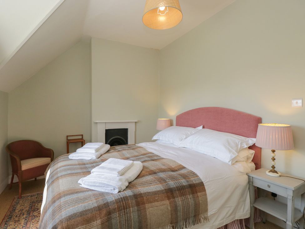 A bedroom with a bed and armchair at Middle Cottage in Tisbury, Wiltshire
