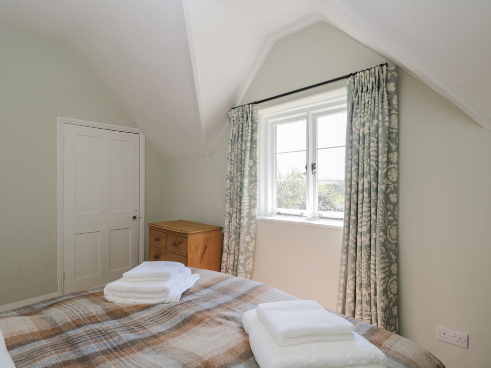 A bedroom with a bed and towels at Middle Cottage in Tisbury, Wiltshire