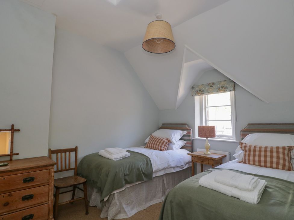 A bedroom with two beds and a wooden furniture at Middle Cottage in Tisbury, Wiltshire