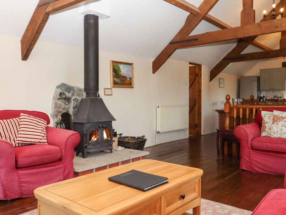 A living room with a stove and seating area at The Cottage in Sampford Courtenay