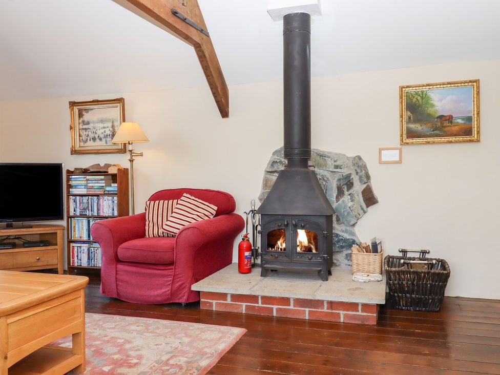 A living room with a fireplace and a red sofa at The Cottage in Sampford Courtenay