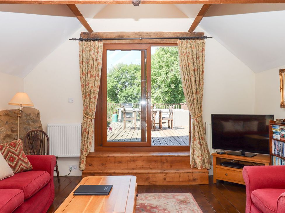 A living room with a sofa and a TV at The Cottage in Sampford Courtenay