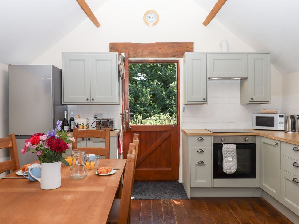 A kitchen with a wooden table and chairs at The Cottage in Sampford Courtenay