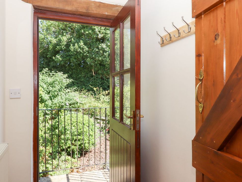 An entrance with an open door and hooks on the wall at The Cottage in Sampford Courtenay