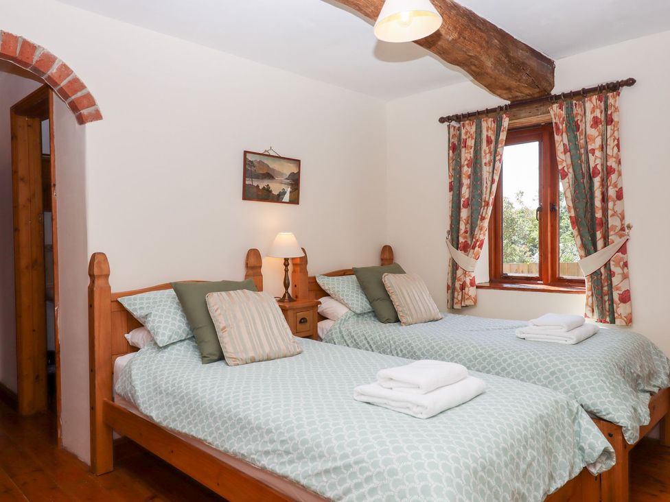A bedroom with two beds and a window at The Cottage in Sampford Courtenay