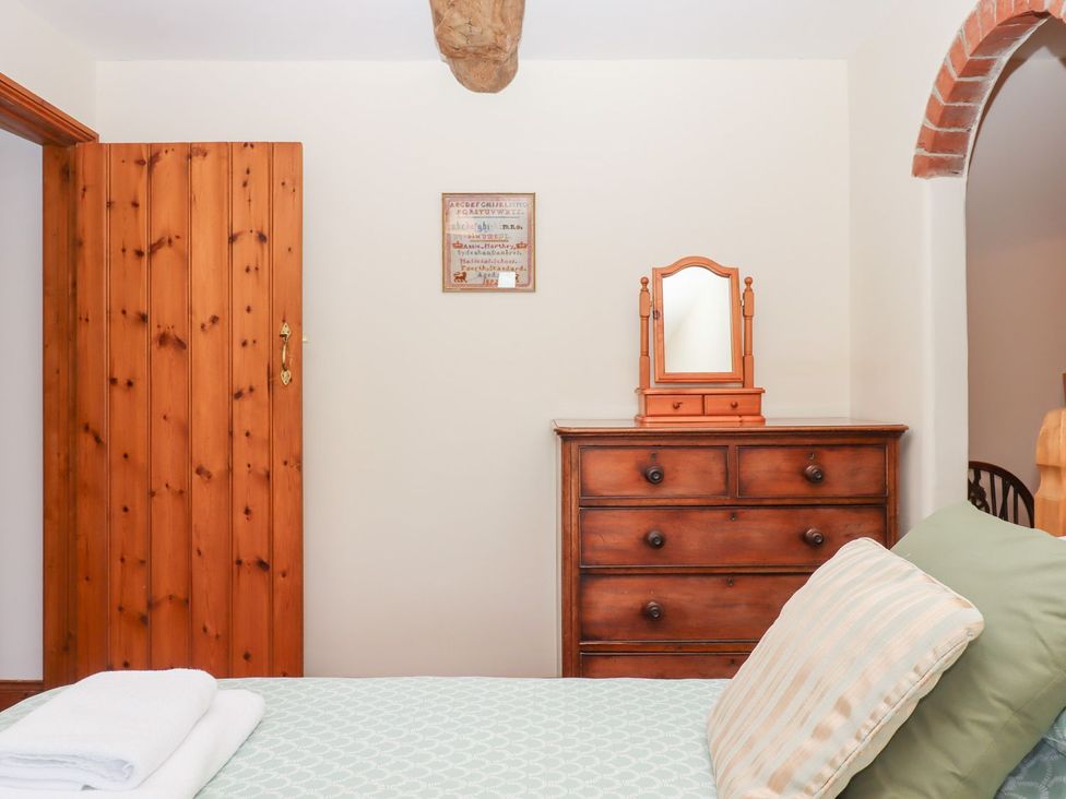 A bedroom with a mirror and chest of drawers at The Cottage in Sampford Courtenay