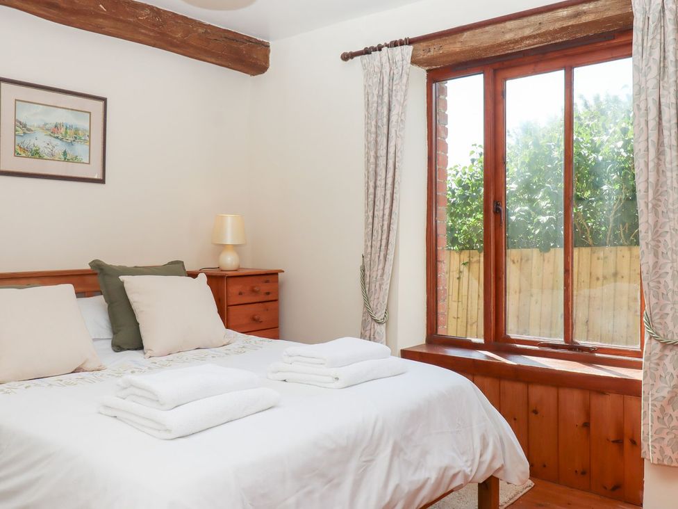 A bedroom with a bed and a window at The Cottage in Sampford Courtenay