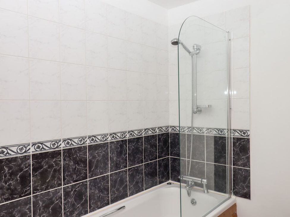 A bathroom featuring a bathtub and shower enclosure at The Cottage in Sampford Courtenay