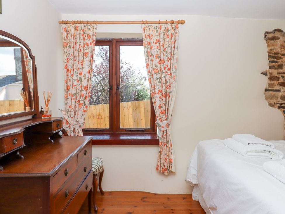 A bedroom with a dresser and a window at The Cottage in Sampford Courtenay