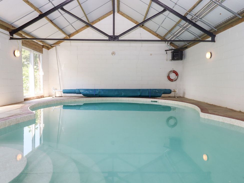An indoor pool with a pool cover at The Cottage in Sampford Courtenay