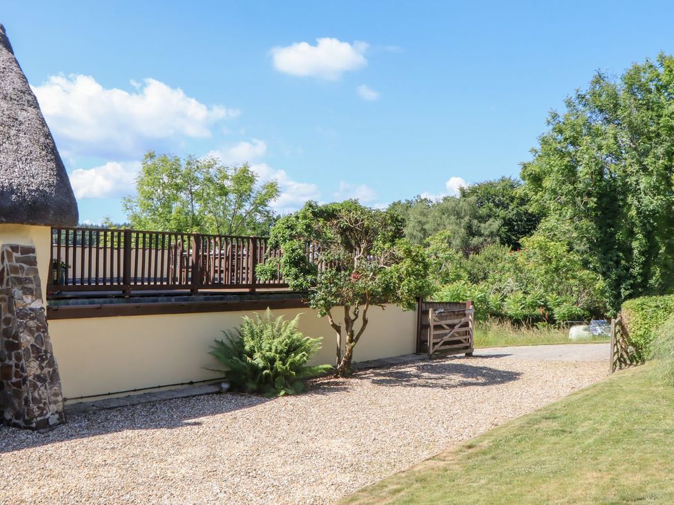 An outdoor area with a thatched roof and gravel path at The Cottage in Sampford Courtenay