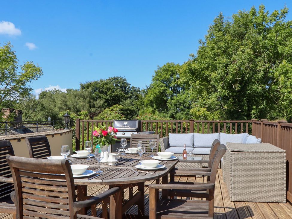 An outdoor seating area with a wooden table and chairs at The Cottage in Sampford Courtenay
