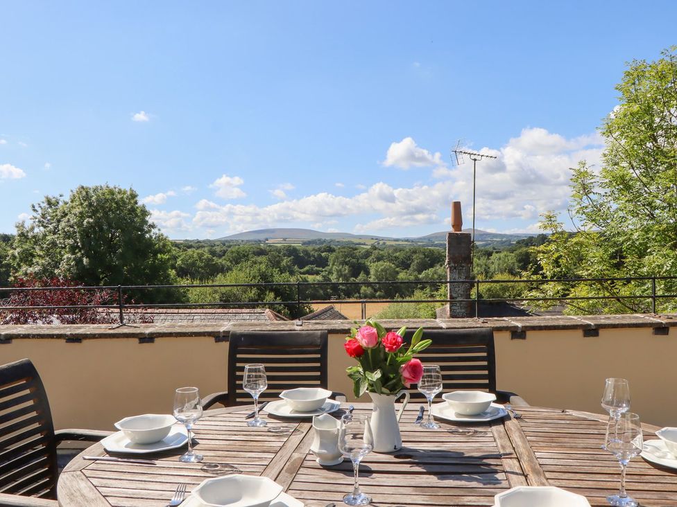 An outdoor dining area with a table set and flowers at The Cottage in Sampford Courtenay