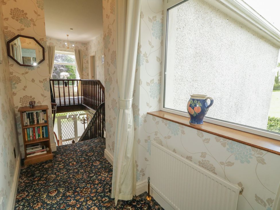 A hallway with a bookshelf and a vase at Riverdene in Mountjoy