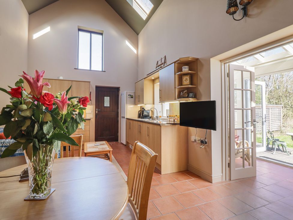 A kitchen with a dining area and flowers on the table at Ystwyth Cottage in Newtown