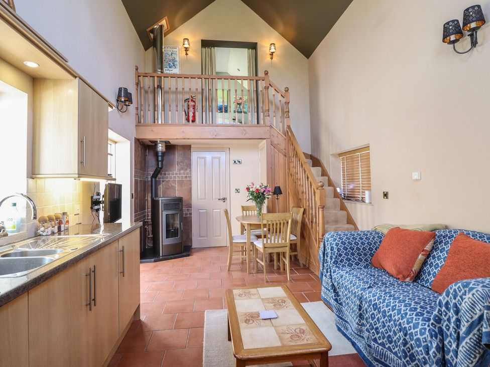 A living room with kitchen appliances and furniture at Ystwyth Cottage in Newtown
