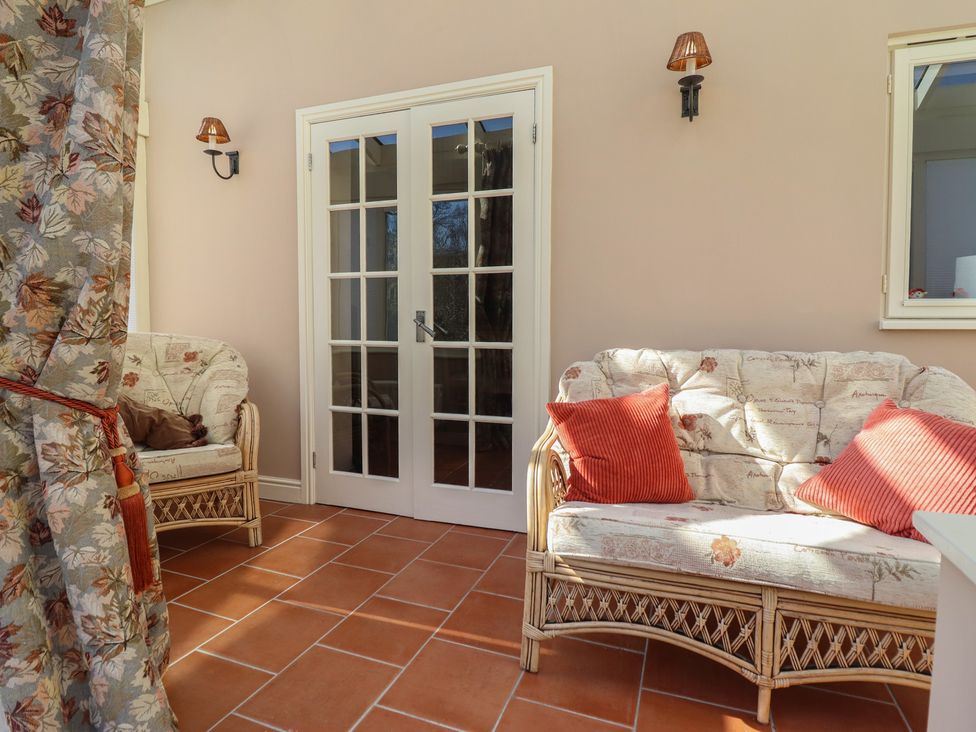 A sunroom featuring double doors and a sofa with cushions at Ystwyth Cottage Newtown