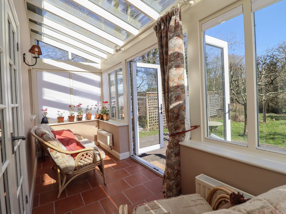 A conservatory with a sofa and flower pots at Ystwyth Cottage in Newtown