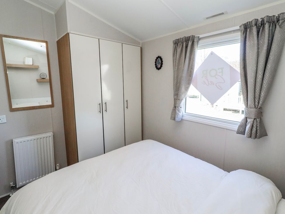 A bedroom with a bed and wardrobe at 75 Morpeth Mews in Wooler