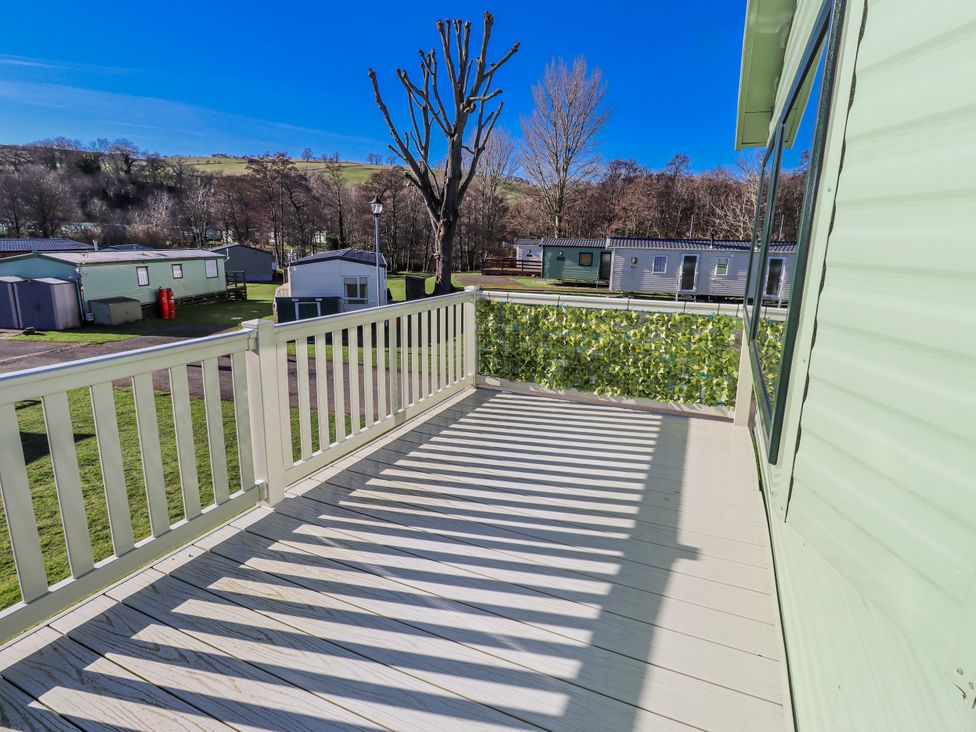 A deck view overlooking caravans and trees at 75 Morpeth Mews in Wooler