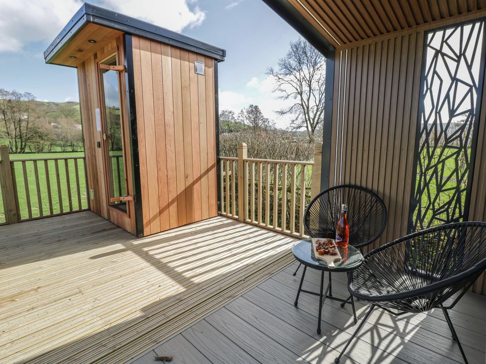 An outdoor seating area with a wooden shed and glass table at Dawn's Rest in Nantmel near Rhayader