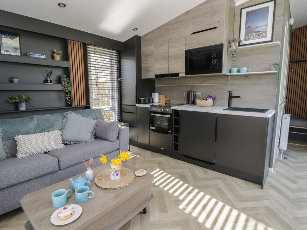 A living room with a sofa and kitchen area at Dawn's Rest in Nantmel near Rhayader